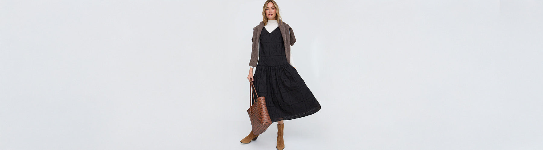 Woman wearing a black dress with a brown jacket on a white background
