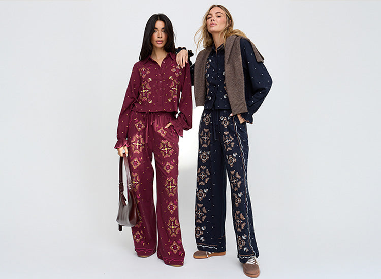 Two women wearing patterned outfits on a white background