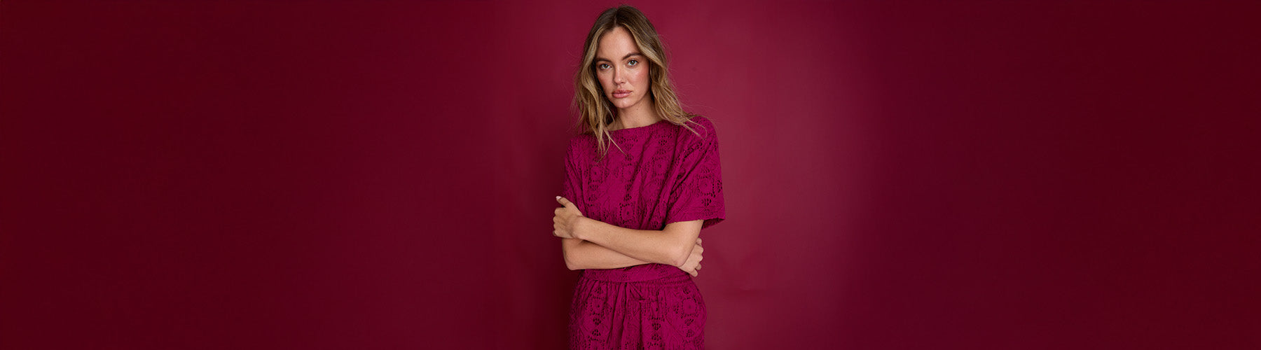 Woman in a pink dress standing against a red background