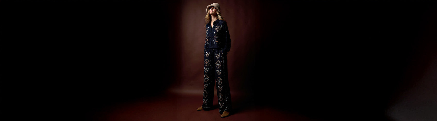 Person wearing a dark outfit with a pattern against a dark background