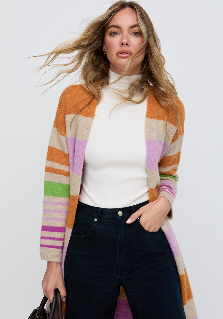 Woman wearing a colorful striped cardigan over a white top and dark jeans on a white background