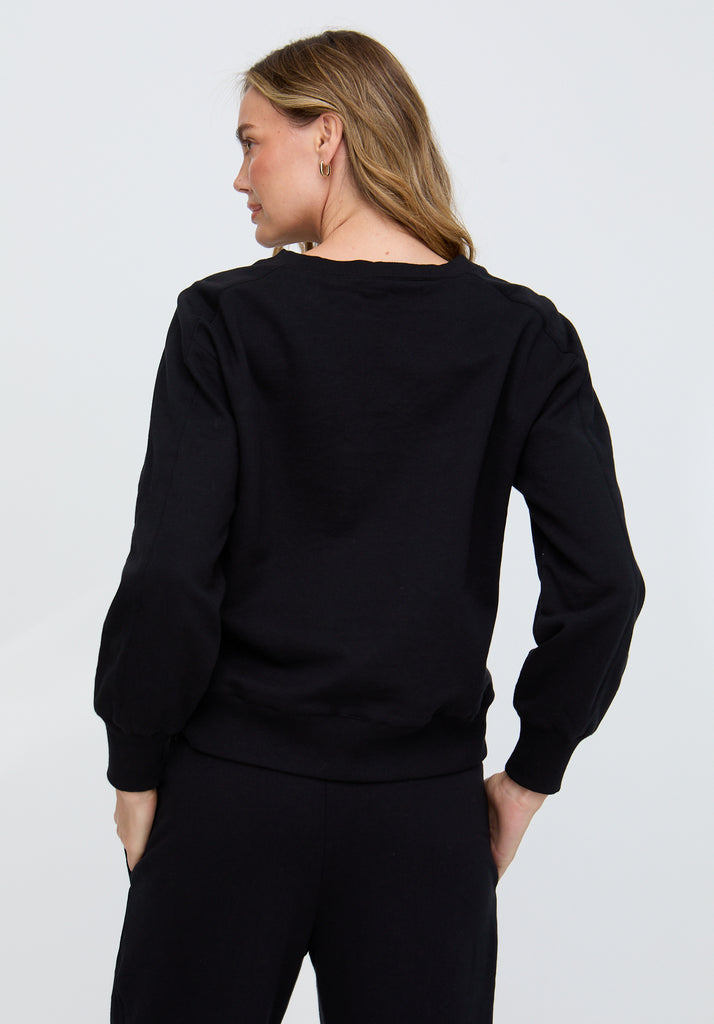Person wearing a black sweater and pants on a plain background