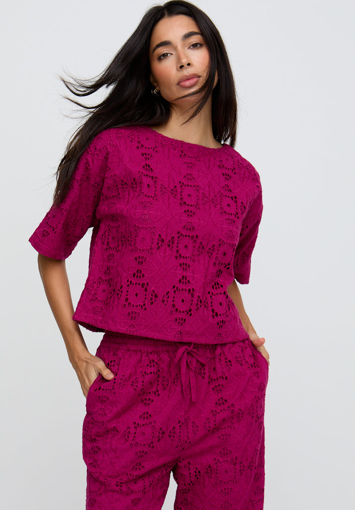 Woman wearing a pink lace outfit on a white background