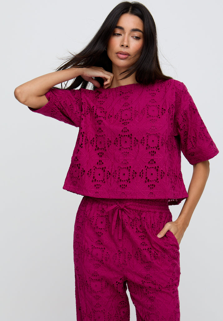 Woman wearing a magenta lace outfit on a white background