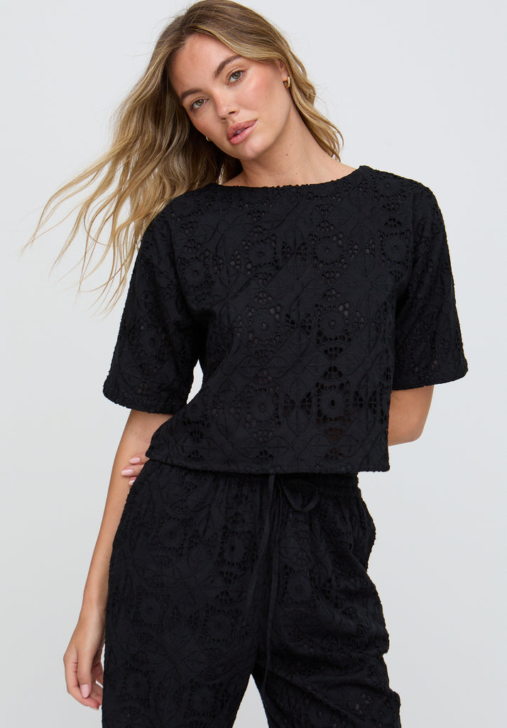 Woman wearing a black lace outfit against a plain background
