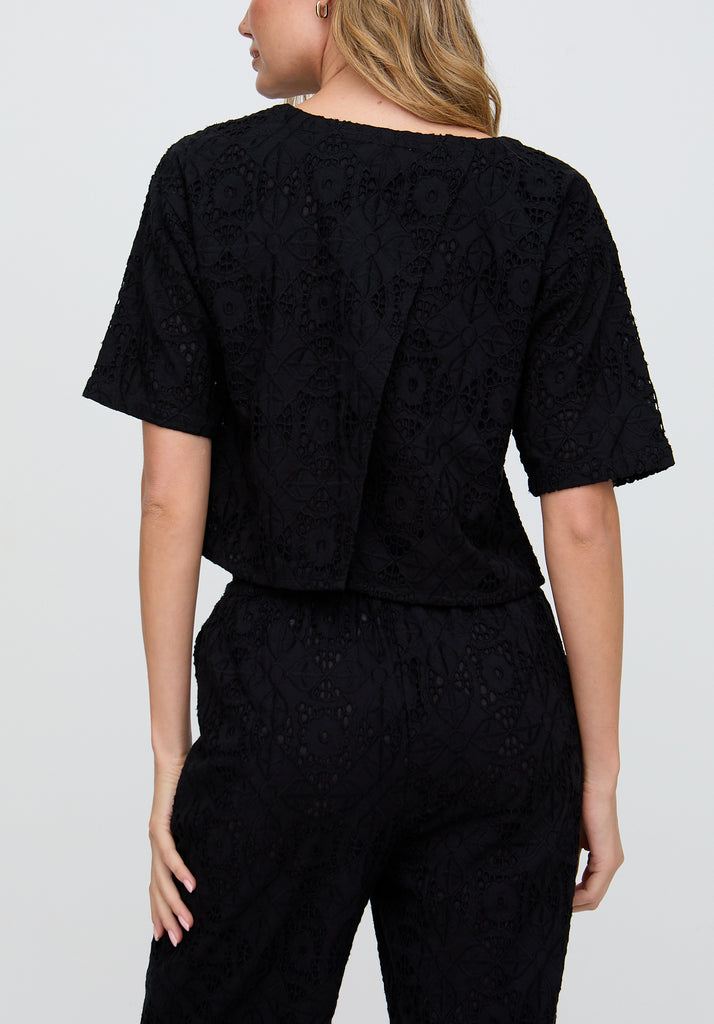 Person wearing a black textured outfit on a plain background