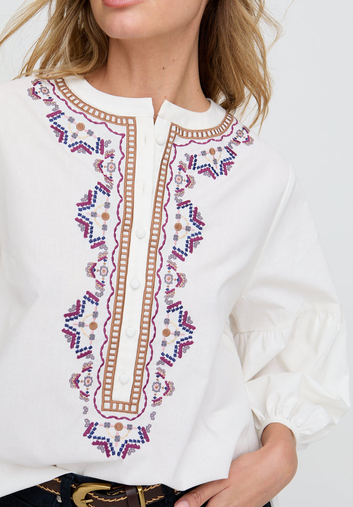 White blouse with intricate embroidery details on a white background