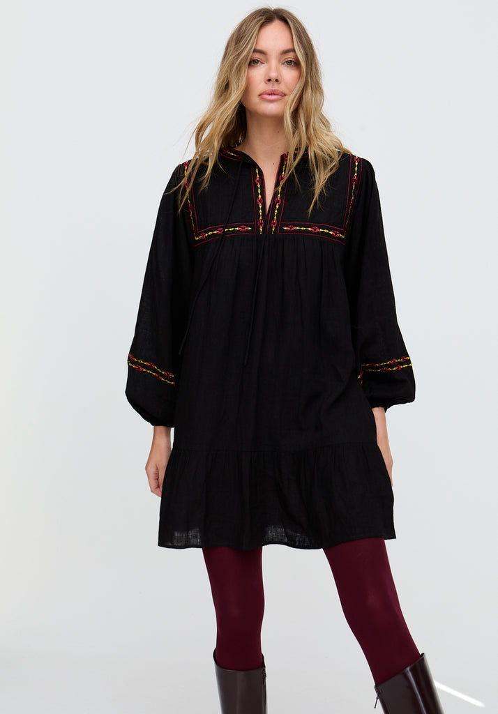 Woman wearing a black dress with red embroidery on a white background