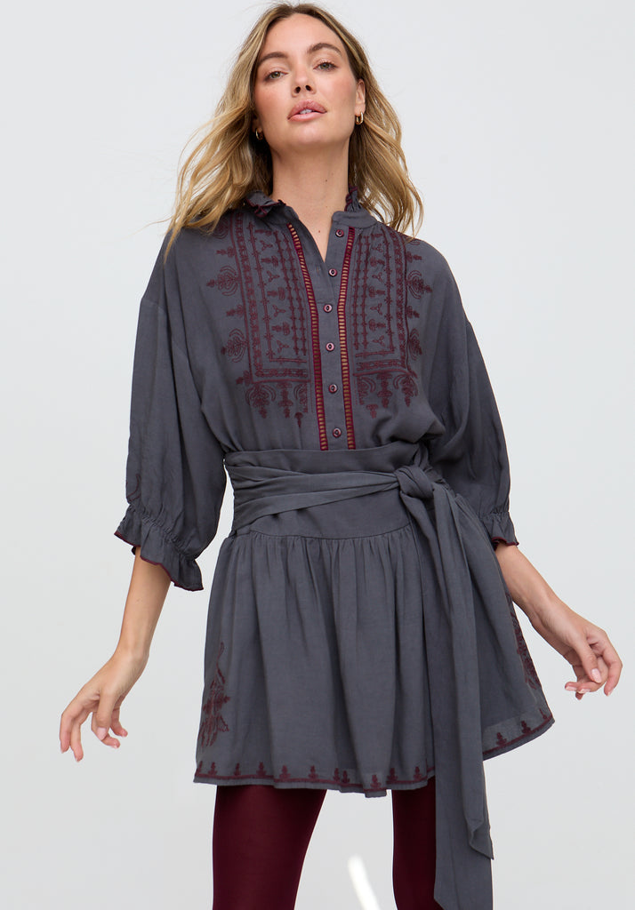 Woman wearing a gray dress with red embroidery on a white background