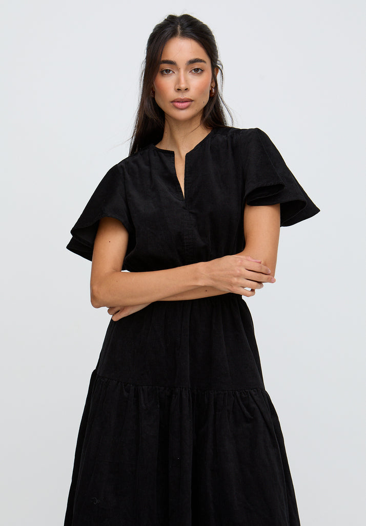 Woman wearing a black dress against a plain background