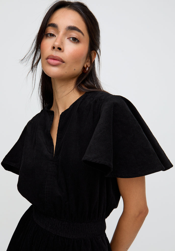 Woman wearing a black dress against a plain background