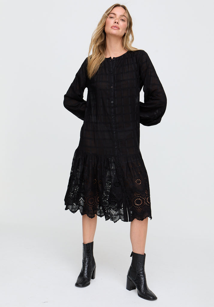 Woman wearing a black dress with lace details on a white background