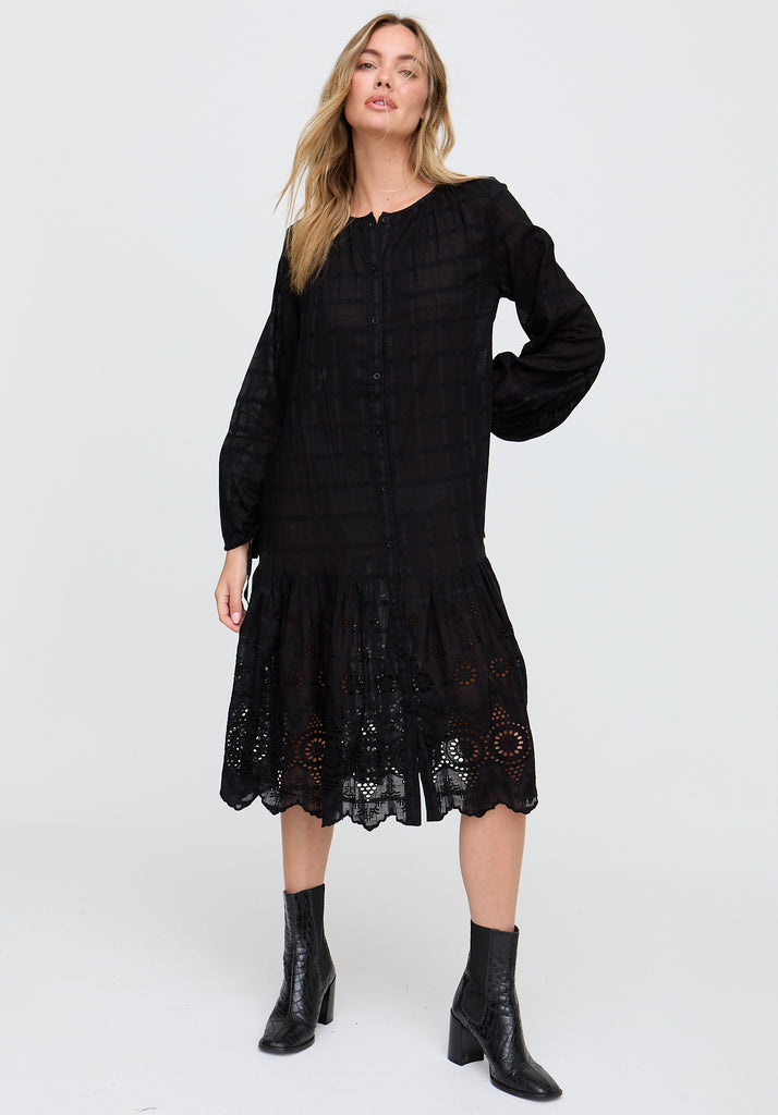 Woman wearing a black dress with lace details on a white background