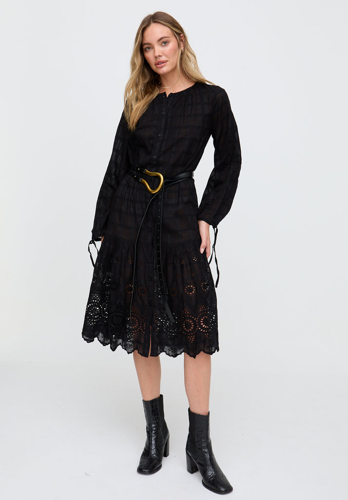 Woman wearing a black dress with lace details and black boots on a white background