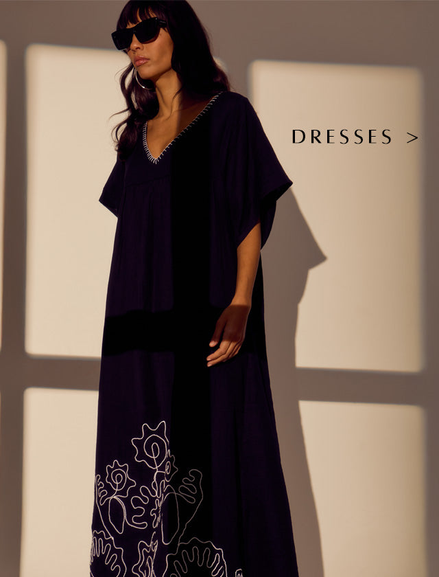 Model styles our Candy Tabard Embroidered Hem Midi Dress In Black. Copy on image 'Dresses'.