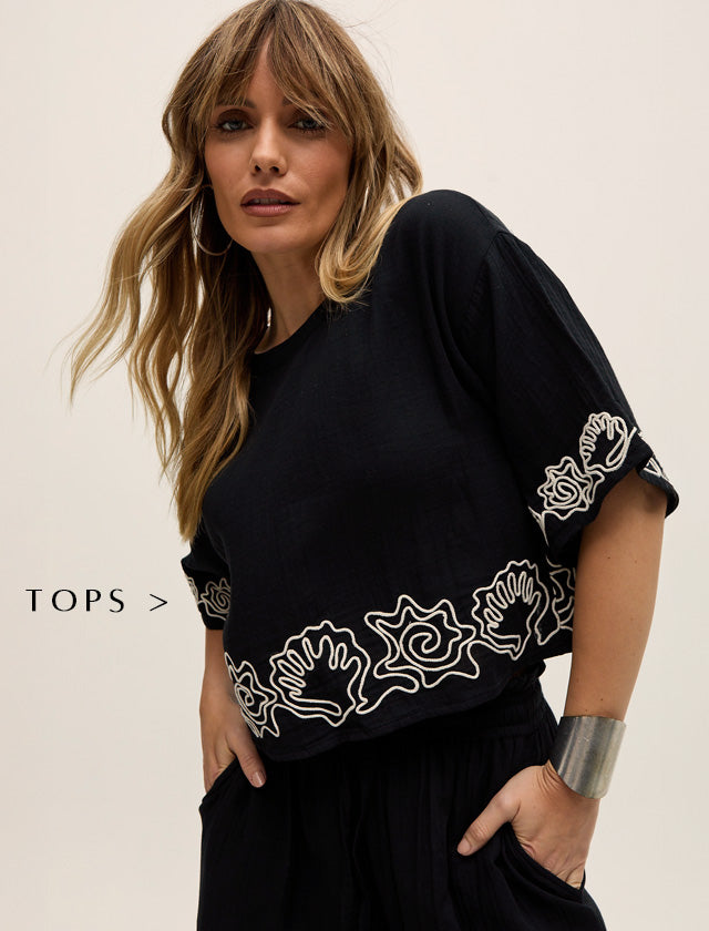 Model styles our Milly Embroidered Split Open Back Blouse In Black. Copy on image 'Tops - Shop Now'.