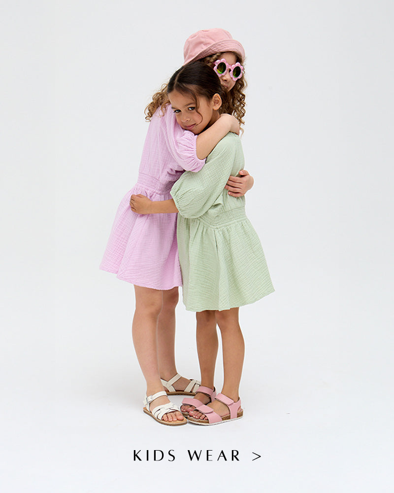 Models wear Kids Soipoi Ruched V-Neck Dress In Green and matching Kids Soipoi Ruched V-Neck Dress In Purple. Copy on image 'Shop Kids Wear'.