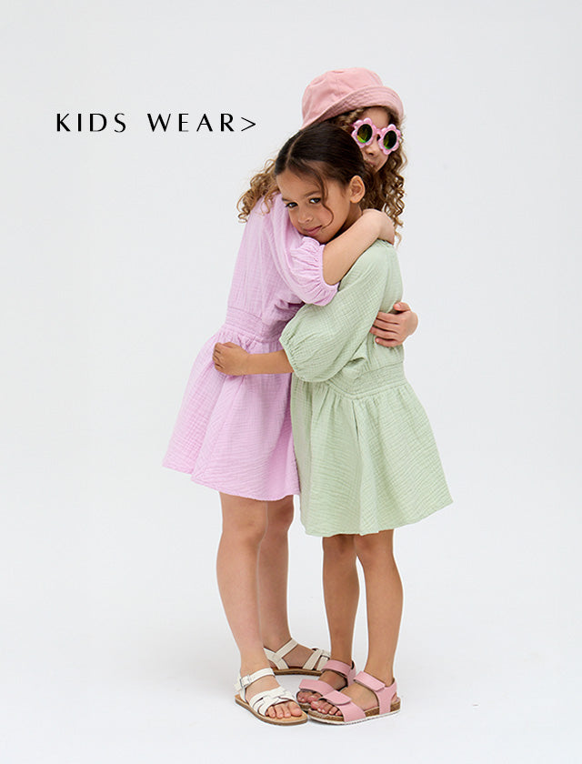 Models wear Kids Soipoi Ruched V-Neck Dress In Green and matching Kids Soipoi Ruched V-Neck Dress In Purple. Copy on image 'Shop Kids Wear'.