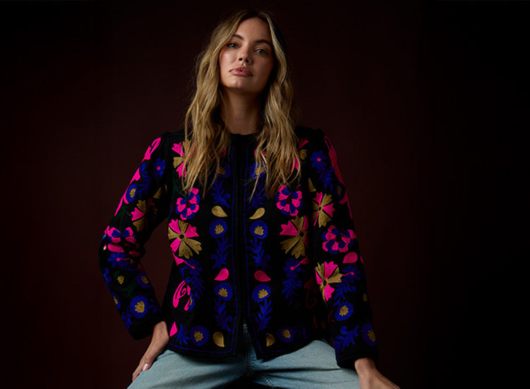 Woman wearing a colorful floral jacket against a dark background