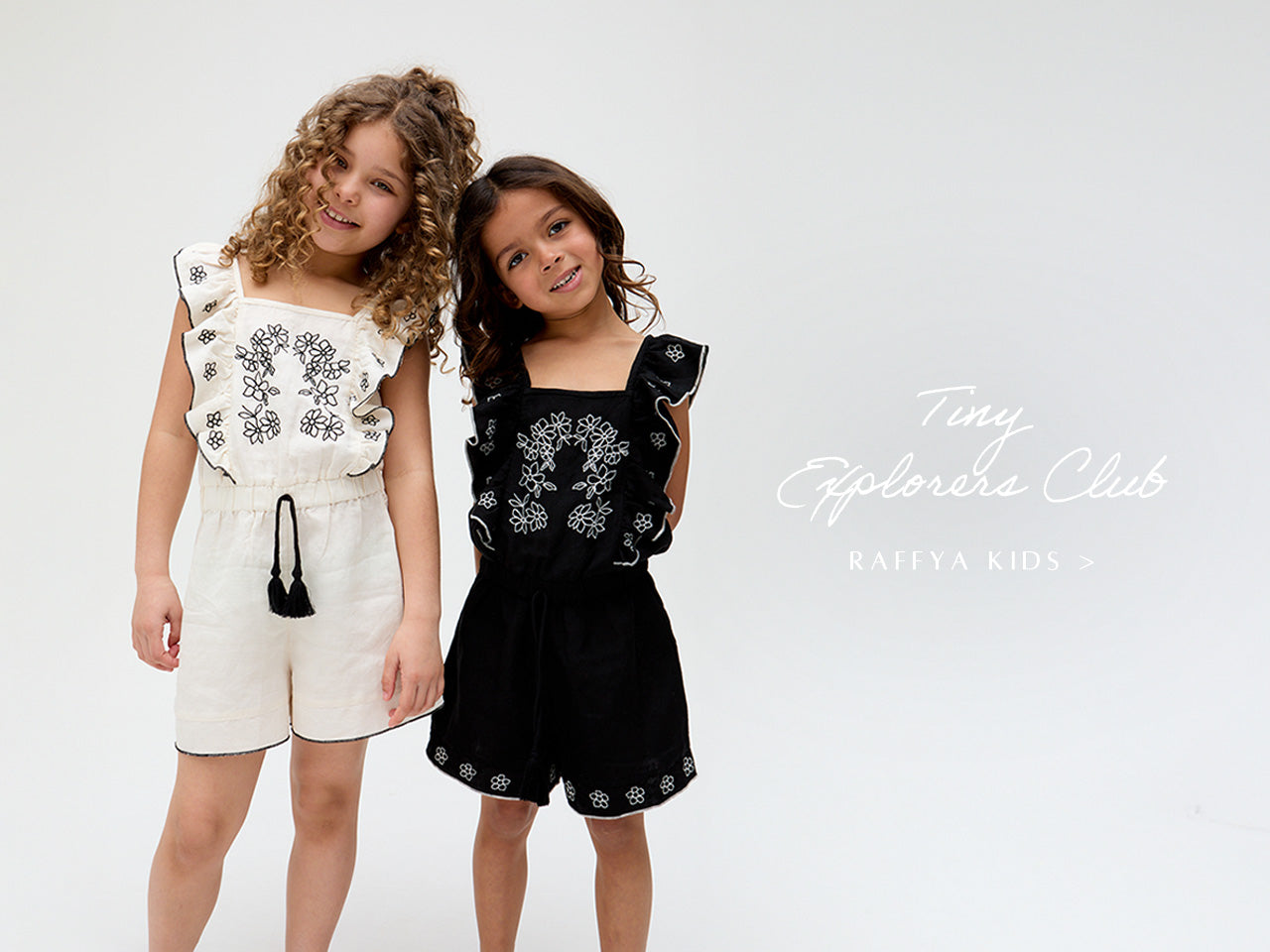 Kids Philo Ruffle Neck Embroidered Playsuit In White and matching Kids Philo Ruffle Neck Embroidered Playsuit In Black. Copy on image 'Tiny Explorers Club - Shop Raffya Kids'.