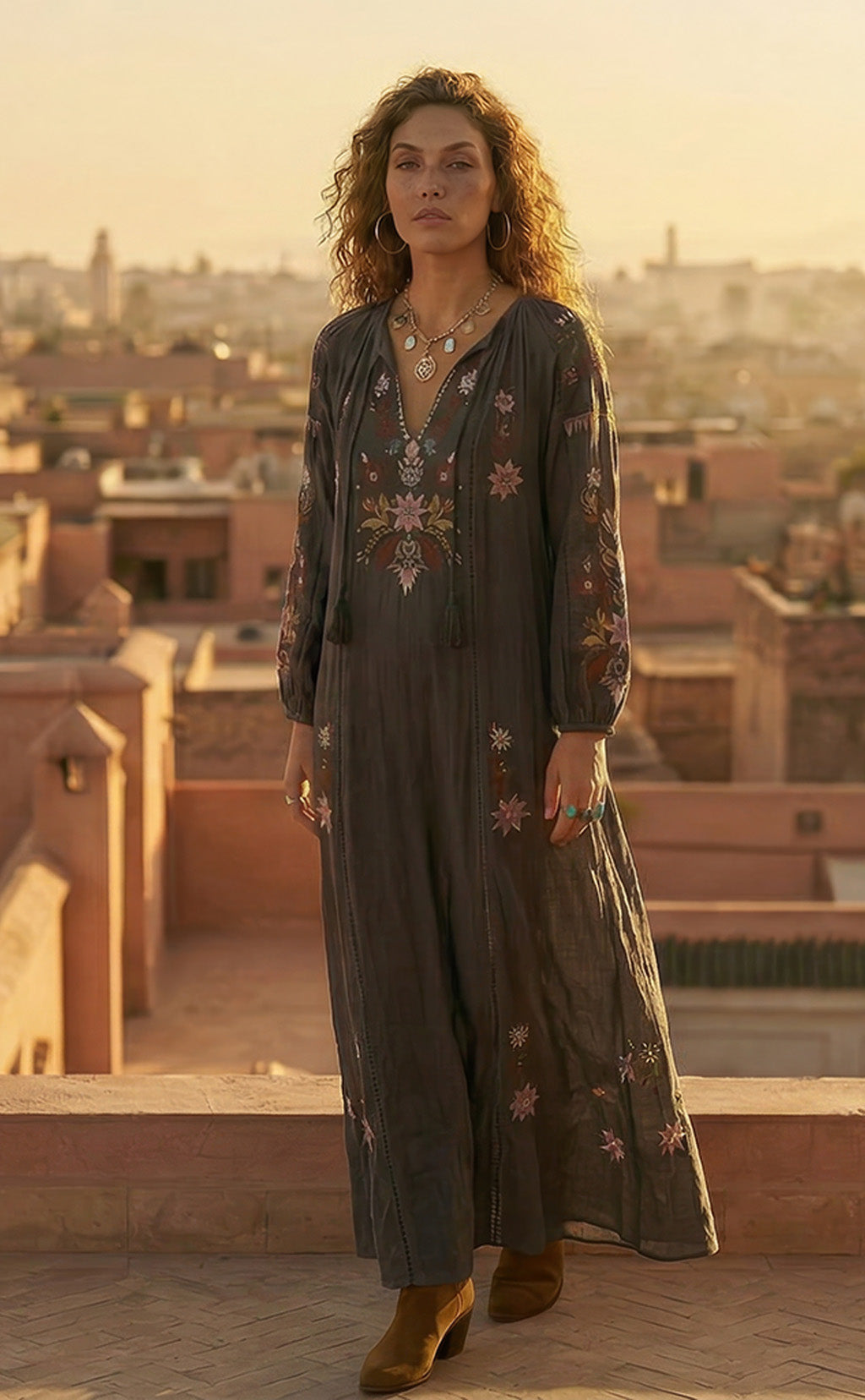 Woman in an embroidered dress standing on a rooftop with a cityscape in the background